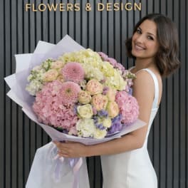 Woman holding a large pastel bouquet of roses, hydrangeas, and dahlias