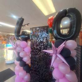 Balloon display with large black 40 numerals and pink, black, and lavender balloons