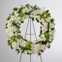 Large white and green floral wreath displayed on a metal easel