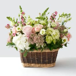 Pink and white mixed flower arrangement in a wicker basket