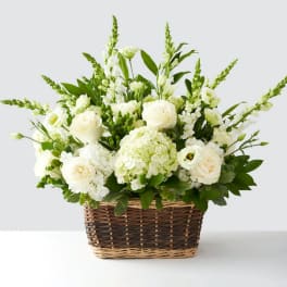White floral arrangement in a wicker basket with tall green spikes