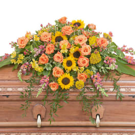 Casket spray with peach roses and yellow sunflowers
