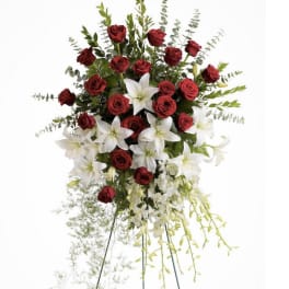 Standing floral spray with red roses and white lilies on a metal easel