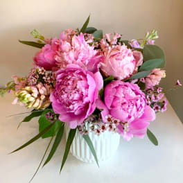 Pink peonies and small pink flowers arranged in a white vase
