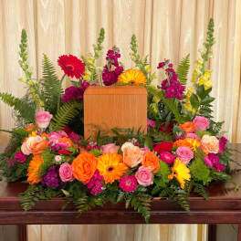 Colorful floral arrangement surrounding a wooden urn on a table