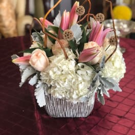 Pink lilies and pale roses arranged with white hydrangeas in a basket