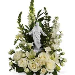 White floral arrangement with a small religious statue in the center