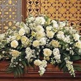 Large white floral casket spray with cascading blooms