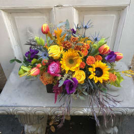 Colorful mixed bouquet with sunflowers, roses, and tulips in a black container