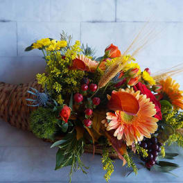 Cornucopia arrangement with orange and yellow flowers in a woven horn basket