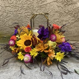 Colorful floral arrangement around a lantern with a candle