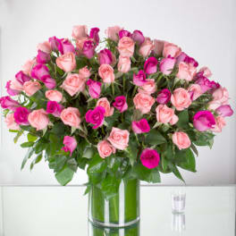 Large bouquet of light pink and hot pink roses in a tall clear glass vase