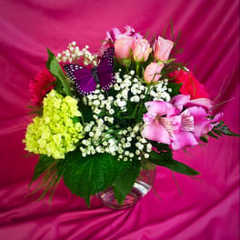 Mixed bouquet of pink roses, lilies, and baby’s breath in a glass vase