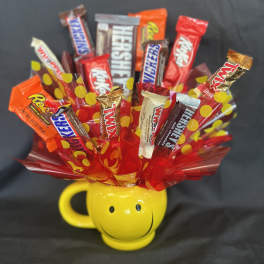 Candy bouquet in a yellow smiley-face mug with assorted chocolate bars