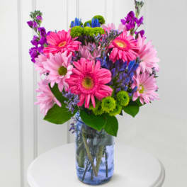 Colorful bouquet of daisies and mixed blooms in a blue glass vase