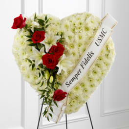 Heart-shaped funeral spray with red roses and white flowers on an easel