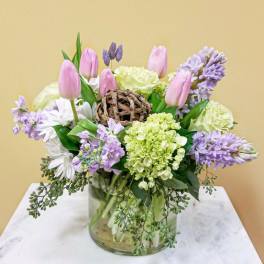 Pink tulips and lavender flowers arranged in a glass vase