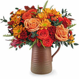 Bouquet of orange roses and yellow daisies in a brown pitcher vase