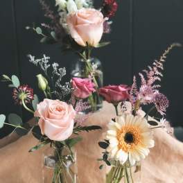 Small mixed bouquets in glass vases with roses and a gerbera daisy