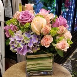 Bouquet of pink and lavender roses with purple hydrangea in a glass vase
