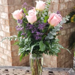 Pink roses and purple filler flowers in a clear glass vase