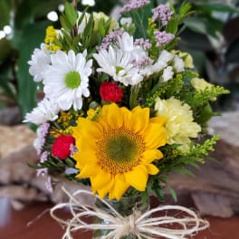 Bouquet with a sunflower, white daisies, and red carnations in a glass vase