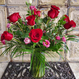 Red roses and pink lisianthus in a clear glass vase