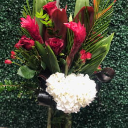 Red and white floral arrangement in a tall glass vase
