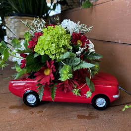 Red flower arrangement in a toy car planter