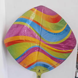 Rainbow-striped foil balloon against a white wall