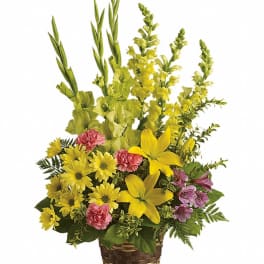 Yellow and pink mixed flower arrangement in a woven basket