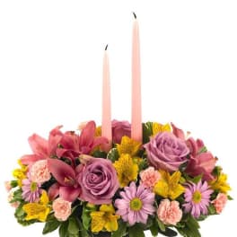 Pink and purple floral centerpiece with two tall taper candles