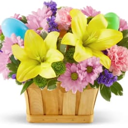 Colorful bouquet with yellow lilies and pink daisies in a wooden basket