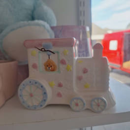 A small painted toy truck with a bear face sits on a shelf.