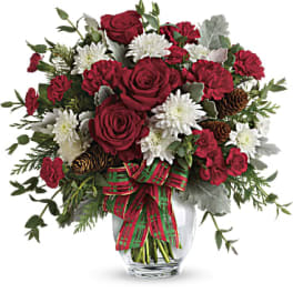 Red roses and white flowers in a glass vase with a plaid ribbon