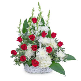 Red roses and white flowers in a white basket arrangement