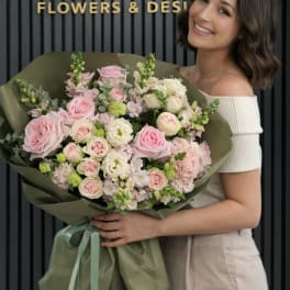 Woman holding a large bouquet of pink and white flowers wrapped in green paper