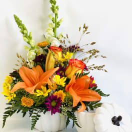 Orange lilies and mixed flowers in white pumpkin containers