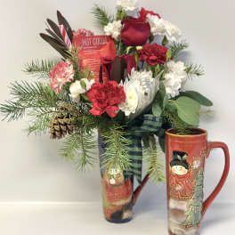 Holiday bouquet with red and white flowers in a tall mug and cocoa packet