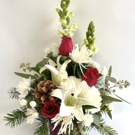 Red roses and white lilies in a square vase with pinecones