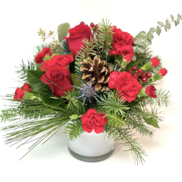 Red roses and carnations in a white vase with pine and a pinecone