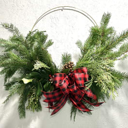 Evergreen holiday swag with a red plaid bow on a metal hanger