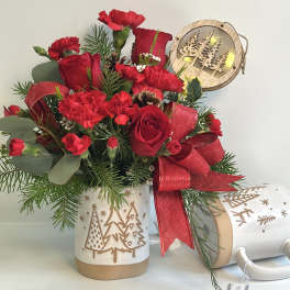 Red roses and carnations in a holiday mug with a red ribbon