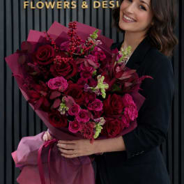 Woman holding a large bouquet of deep pink and red roses