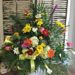 Large mixed flower arrangement with bright gerberas, calla lilies, and roses
