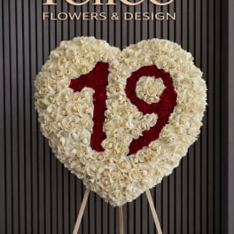 Heart-shaped rose arrangement on a stand with red lettering
