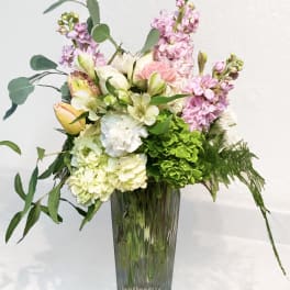 Pastel floral arrangement in a tall glass vase with pink and white blooms