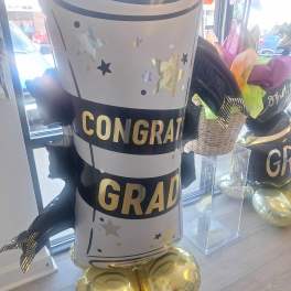 Graduation-themed balloon display shaped like a diploma with gold balloons at the base