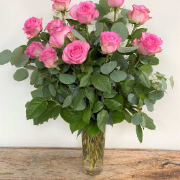 Pink roses arranged in a clear glass vase with eucalyptus foliage