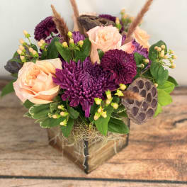 Peach roses and purple chrysanthemums in a wooden box with dried pods